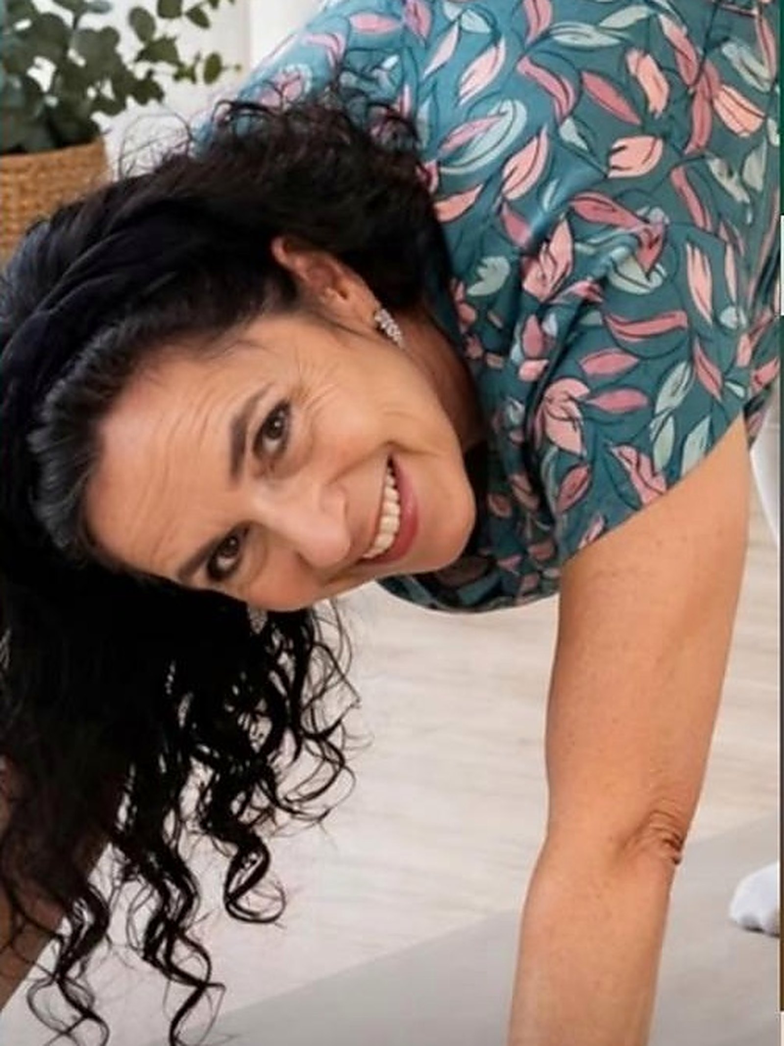 Birgit Auerbach lächelt in einer Vorwärtsbeuge im Yogastudio