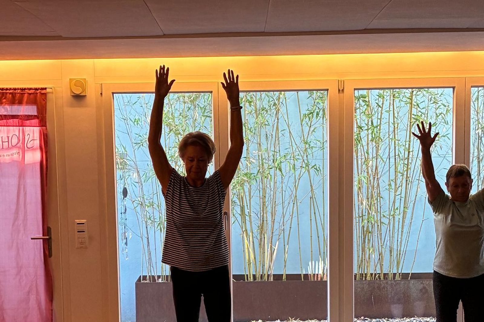 Teilnehmerinnen heben im Studio Soham Yoga gemeinsam die Arme über den Kopf