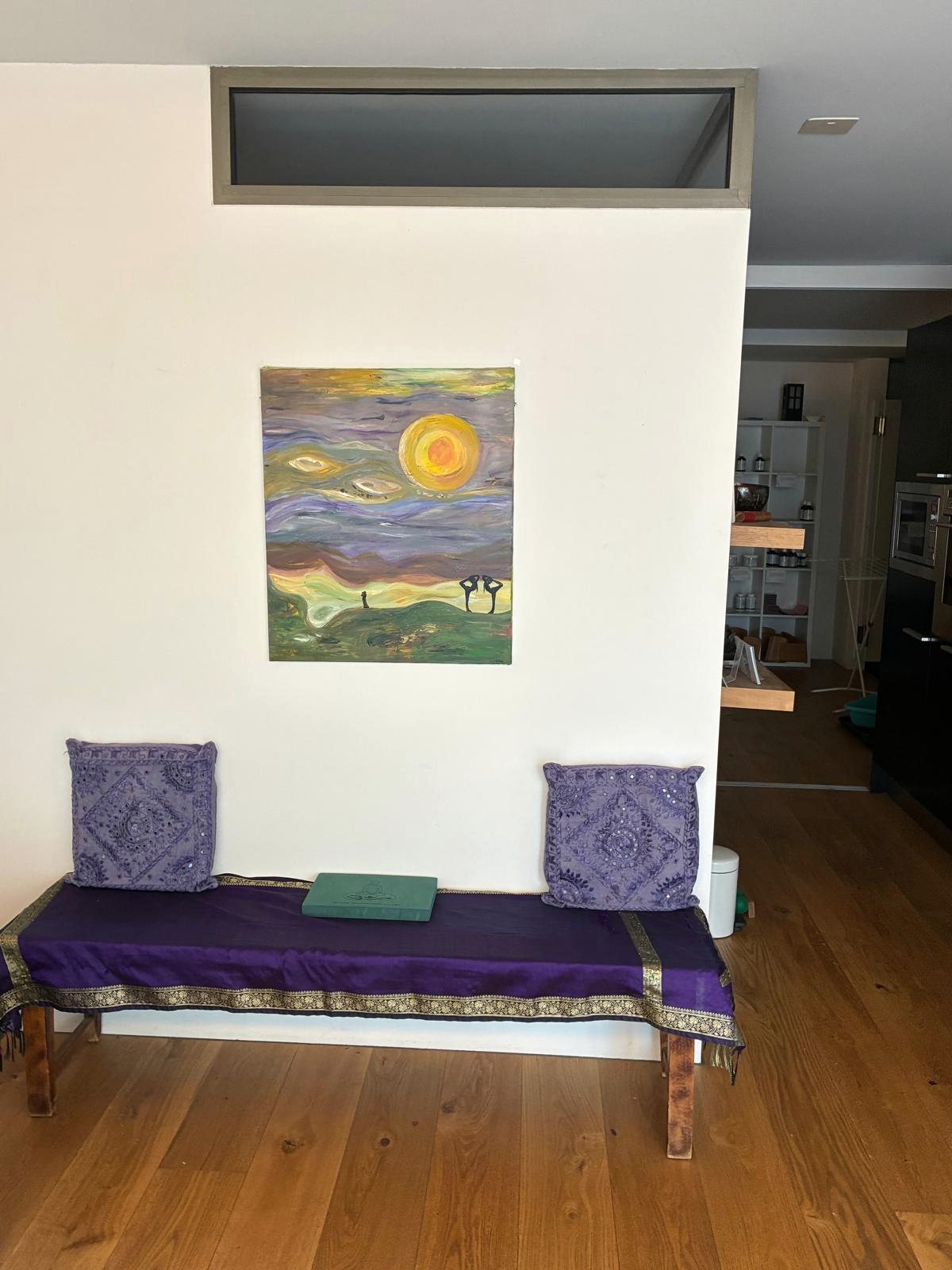 Sitzbank mit violetten Kissen unter einem Bild im Eingangsbereich des Studios