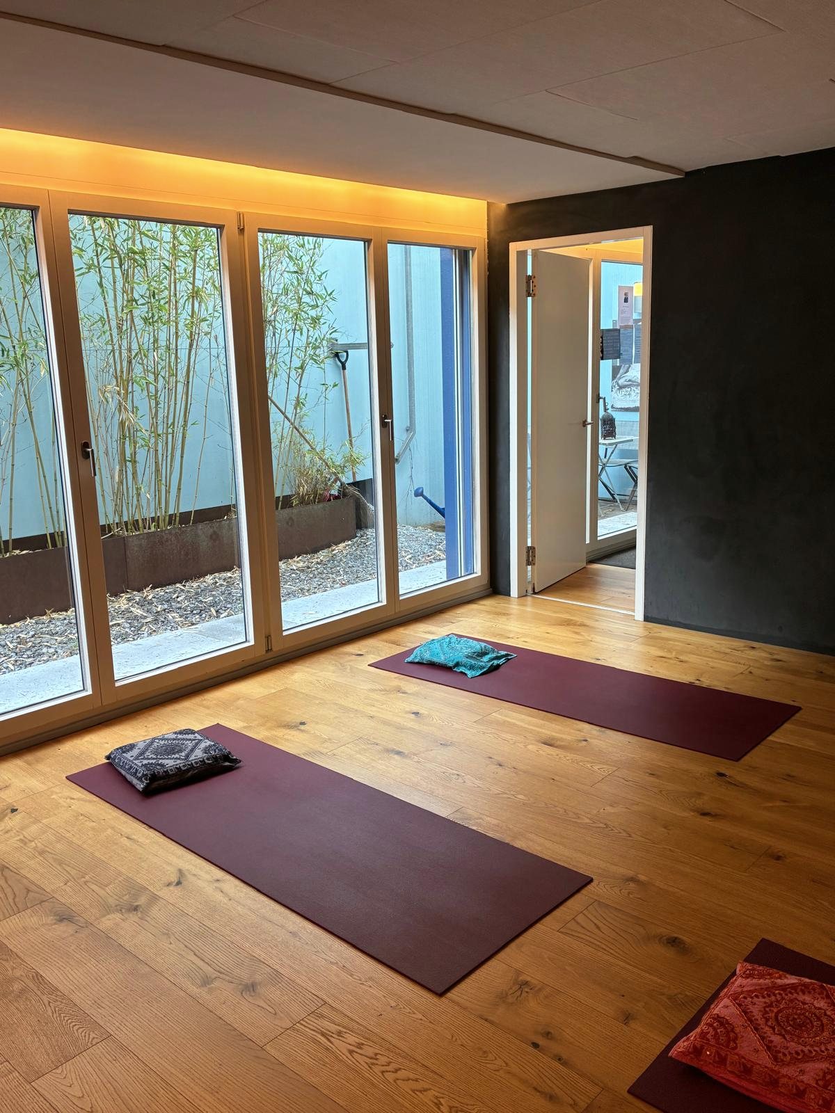 Der Yogaraum von Soham Yoga mit Fensterfront und ausgelegten Matten